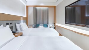 Une chambre d’hôtel avec deux lits, une télévision, un bureau et une fenêtre avec des rideaux.