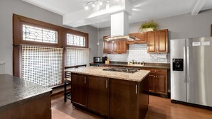 A modern kitchen with a central island, stainless steel appliances, and wooden cabinetry.