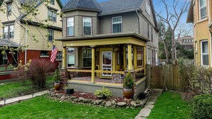 A two-story house with a porch, a stone foundation, and a well-maintained lawn.