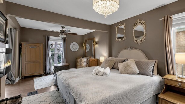 A bedroom with a large bed, a chandelier, a ceiling fan, and a wardrobe.