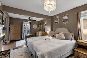 A bedroom with a large bed, a chandelier, a ceiling fan, and a wardrobe. - Charming 5 BR Grand Victorian Family Home King Suite Walk to Falls Game-Room (Niagara Falls)