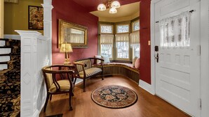 A room with a bay window, a wooden floor, a patterned rug, and a white door.