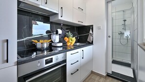 Eine moderne Küche mit weißen Schränken, einer schwarzen Arbeitsplatte und einem eingebauten Backofen.