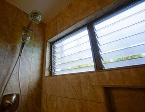 A shower with a window above it, allowing natural light to enter the room.