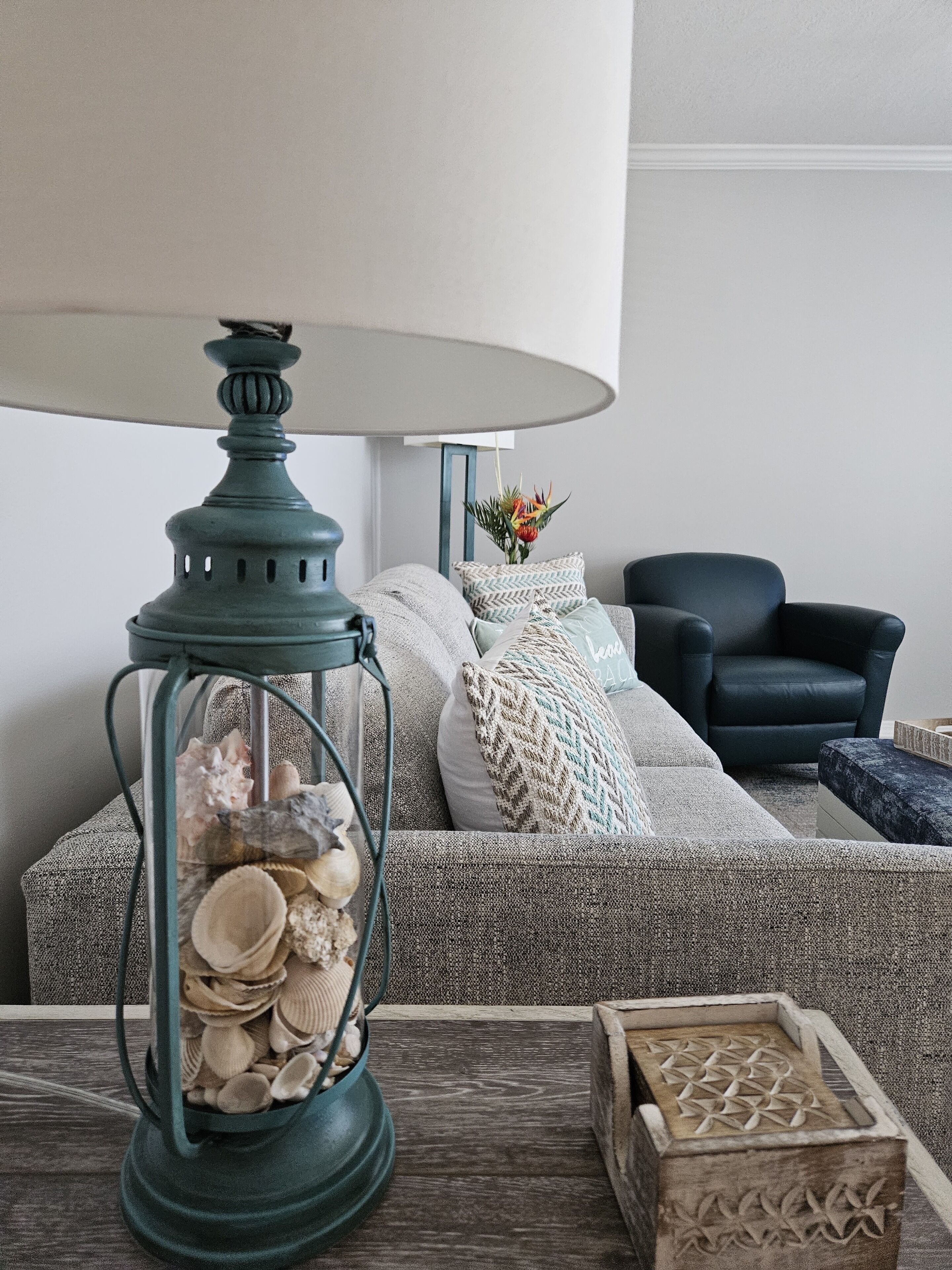 Un salón acogedor con un farol verde, un sofá estampado y un sillón oscuro.