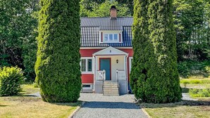 Ein Haus mit roter Fassade, einer weißen Tür und einer kleinen Veranda.
