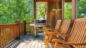 Une terrasse en bois avec un barbecue et quatre chaises en bois.