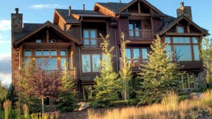 Une grande maison en bois à plusieurs étages, dotée de nombreux balcons et de grandes fenêtres.