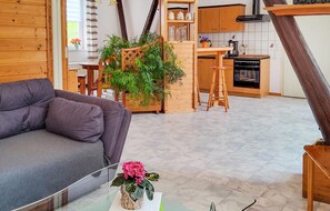 A modern living room with a grey sofa, a wooden dining table, and a kitchen area with wooden cabinets and a stove. - Amazing apartment in Bad Schandau-Kleing. (Bad Schandau-Kleing.)