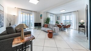 Amplia sala de estar con sofá, mesa de centro, televisor y mesa de comedor con sillas.