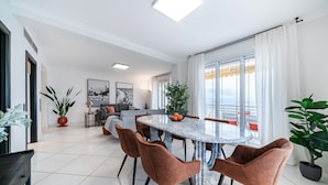 Un comedor moderno con una mesa de mármol, seis sillas marrones y una planta en maceta.