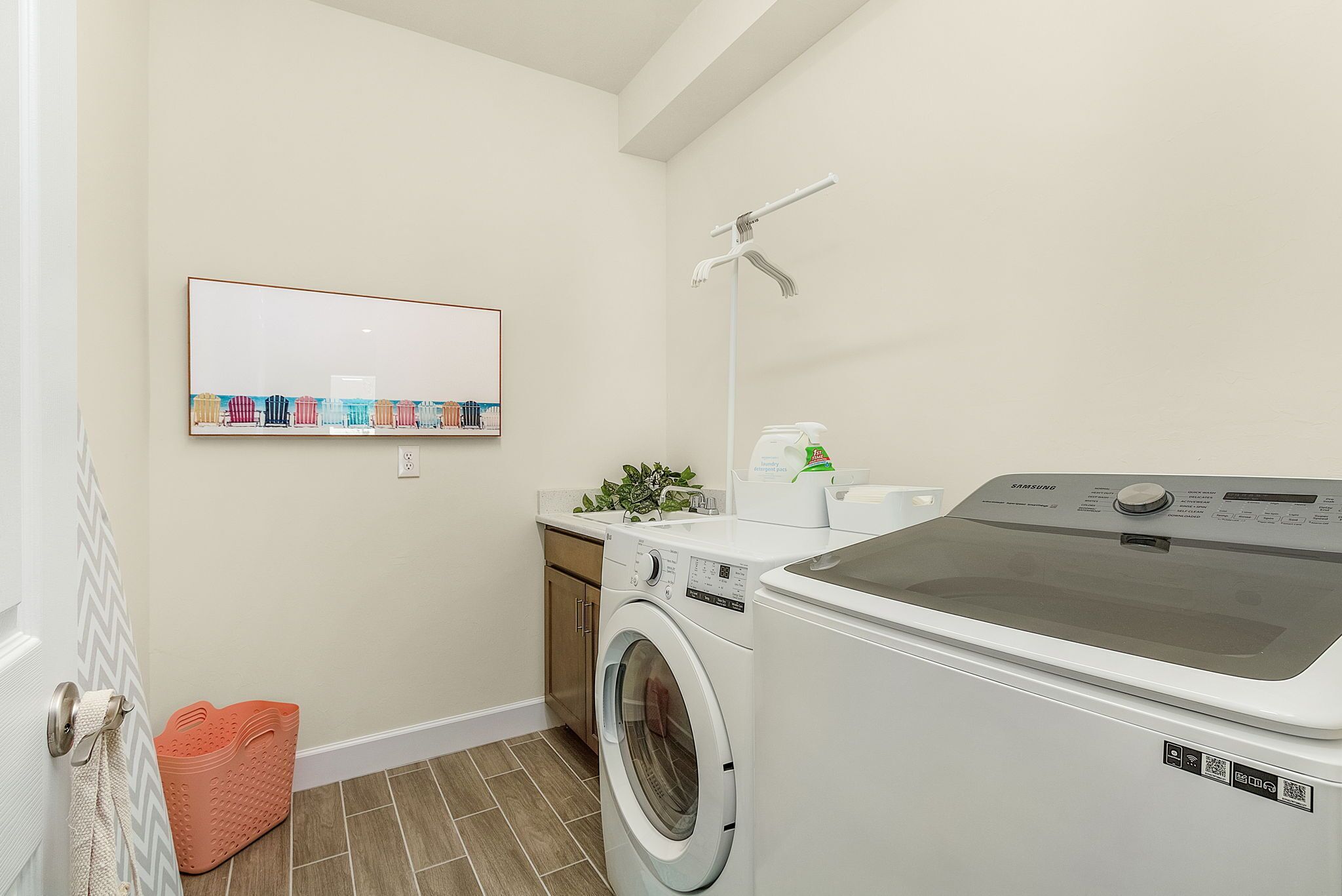 A compact laundry room with a washing machine, dryer, and a wall-mounted shelf with folded clothes.