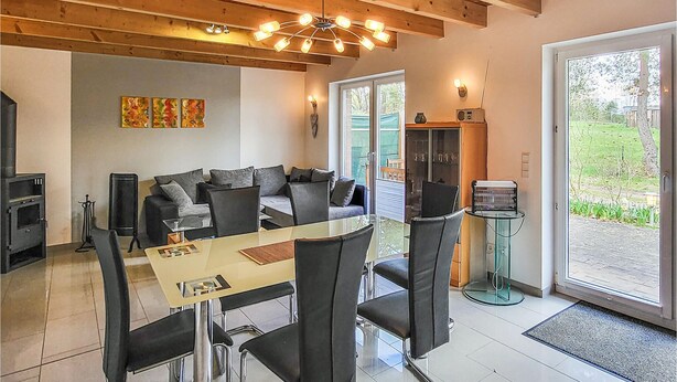 Un salon moderne avec une table à manger en verre, des chaises noires, un canapé et un plafond en bois.