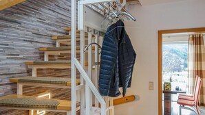 Una escalera de madera con barandilla de metal que conduce a una habitación con vistas a un paisaje nevado.