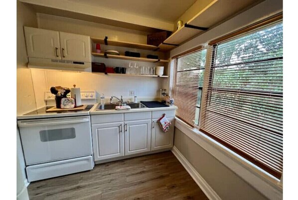 Compact kitchen with oven, sink, and shelves for kitchen essentials.