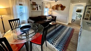 Ein modernes Wohnzimmer mit einem Glastisch, einer Couch und einem Deckenventilator.