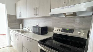 A modern kitchen with stainless steel appliances, grey cabinetry, and a tiled backsplash. - Discover Beautiful Beaches in Fajardo! 3 Bed, 2 Bath home, Pool, BBQ, full AC! (Fajardo)