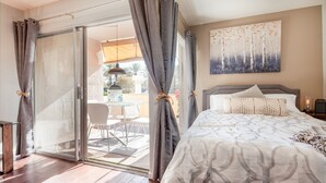 Een slaapkamer met een bed, een schilderij en uitzicht op buiten.
