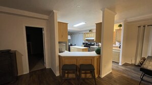 Una cocina moderna con armarios de madera, una isla central con taburetes y un comedor con mesa y sillas.