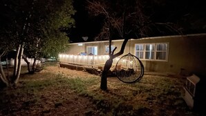 Una casa con patio trasero cercado, un columpio colgando de un árbol y una antena parabólica en el techo.