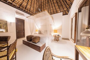 Quarto com cama de dossel, móveis de vime, porta de madeira e ventilador de teto.