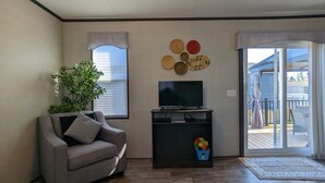 A living room with a grey sofa, a flat-screen TV, a small table, and a plant. - Paradise in Niagara-on-the-lakes at Vine Ridge Resorts.  (Niagara-on-the-Lake)