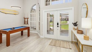 A spacious room with a pool table, large arched windows, and a door leading outside. - Stunning villa with heated saltwater pool, 4 bedrooms, 2 bathrooms and office. (Cape Coral)