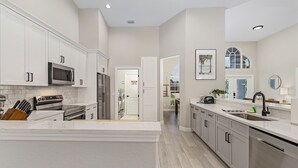 A spacious kitchen with white cabinetry, stainless steel appliances, and a large island. - Stunning villa with heated saltwater pool, 4 bedrooms, 2 bathrooms and office. (Cape Coral)