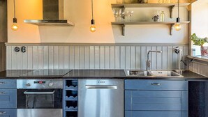 Una cucina moderna con lavastoviglie Bosch, forno integrato, lavello in acciaio inossidabile e portabottiglie.