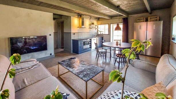 Un soggiorno moderno con una grande TV, comodi posti a sedere, un angolo cottura e un'area pranzo.