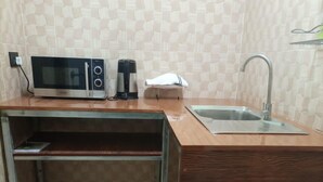 Una cocina compacta con microondas, cafetera y lavabo.