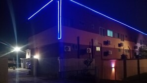 Un edificio con entrada protegida por un portón, unidades de aire acondicionado y un farol.
