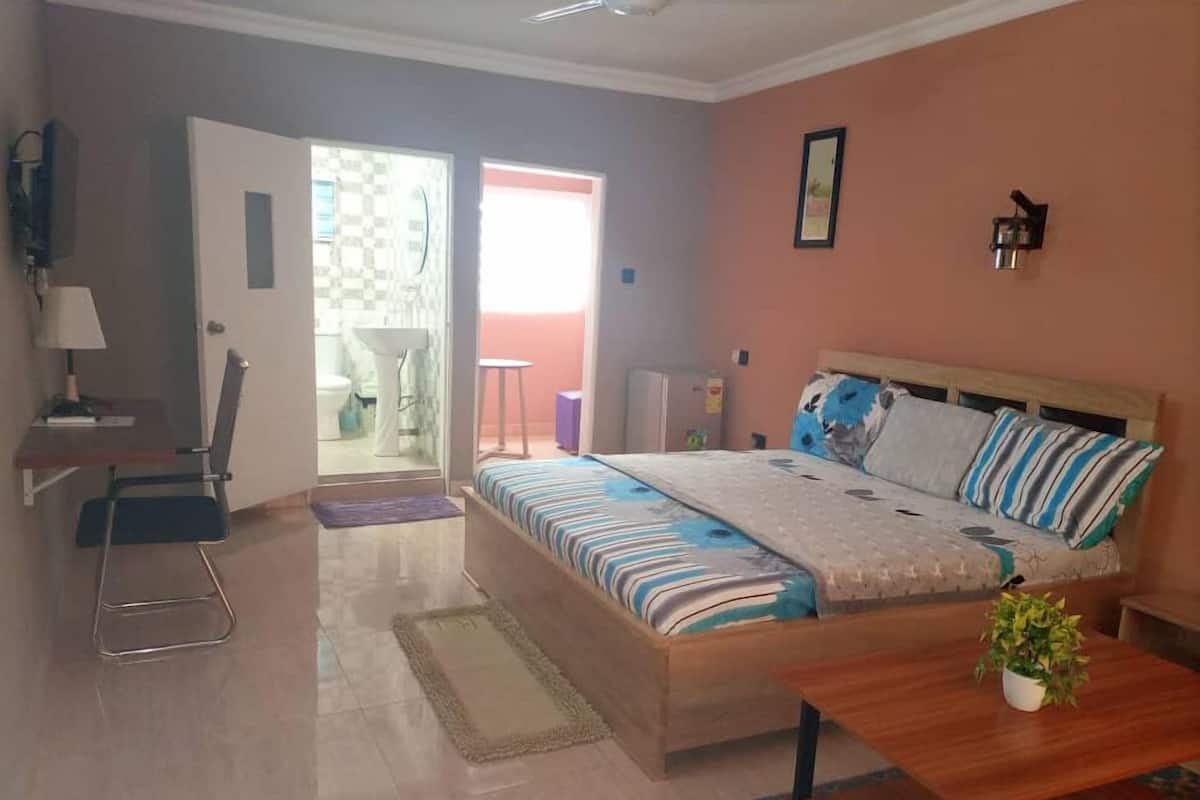 A bedroom with a bed, bedside table, and a small desk with a chair.
