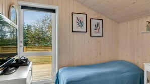 Et soveværelse med en seng, et skrivebord med kogeplade, og to billeder hængende på væggen.