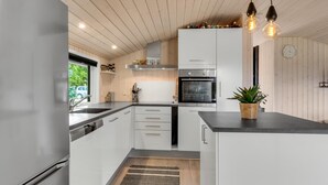 Et moderne køkken med hvide skabe, indbygget ovn og en stor ø med vask.