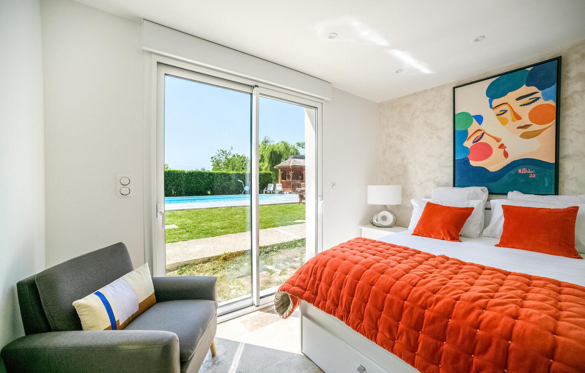 Une chambre avec un lit, une chaise, un tableau et une vue sur une piscine.