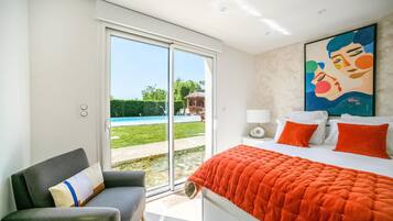 Une chambre avec un lit, une chaise, un tableau et une vue sur une piscine.