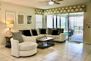 A living room with a sofa, armchair, coffee table, and artwork on the wall.