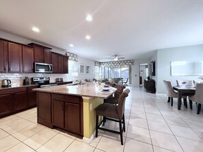A spacious kitchen with dark wooden cabinets, a central island, and a dining area with chairs and a table.