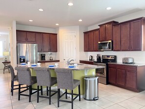 A modern kitchen with dark wooden cabinets, stainless steel appliances, and a central island with bar stools.