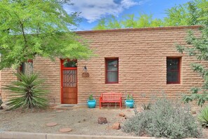 A brick building with a red door, two windows, and a bench in front. - Barrio Viejo, Charming Historic Downtown Home (Tucson)