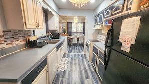 A modern kitchen with a central island, a dining area with chairs, and a refrigerator with a 'No Smoking' sign.