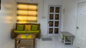 Una sala de estar con un sofá de madera, una mesa de centro y una puerta con paneles de vidrio.
