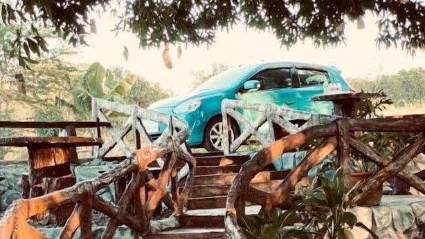 Un puente de madera que conduce a un coche en un entorno natural.