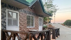 Un edificio de piedra con dos ventanas, una cubierta de madera y un muro de piedra.