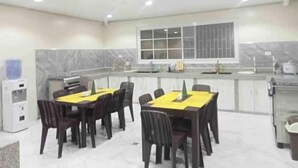 Un comedor con dos mesas, cada una con mantel amarillo y sillas oscuras.