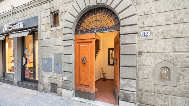 A stone building with a wooden door, a visible shop sign, and a number plaque.