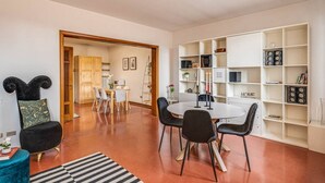 Una sala de estar moderna con comedor, una estantería y una cocina al fondo.