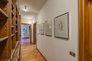 A hallway with wooden paneling, a staircase, and framed artwork on the walls. - Apartments Florence Accademia Charme (Firenze)