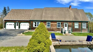 Ein zweistöckiges Gebäude mit Garage, Veranda und Swimmingpool.